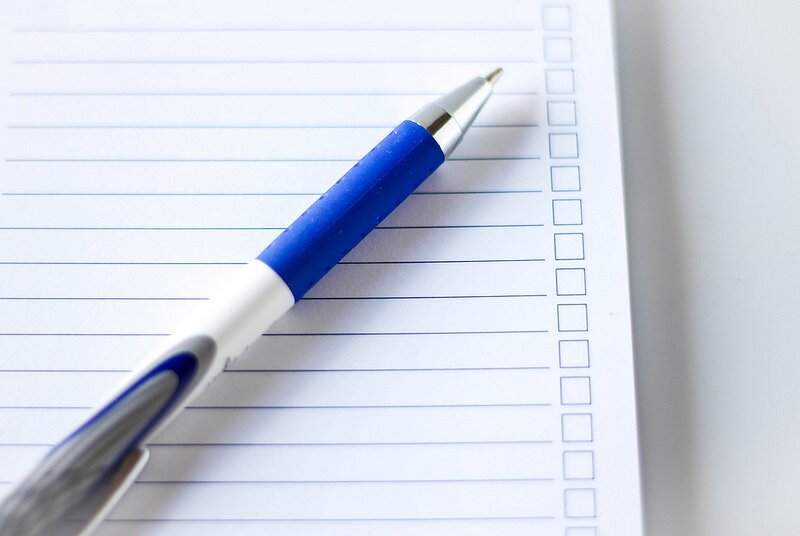 Picture of a white lined pad of paper with a large blue and white pen lying on it diagonally