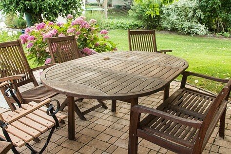 Picture of an outdoor deck with a dark plastic patio set of a large table, chairs and matching bench