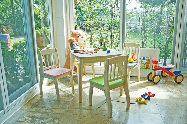 Picture of a sunroom with child size table and chairs surrounded by toys on the floor